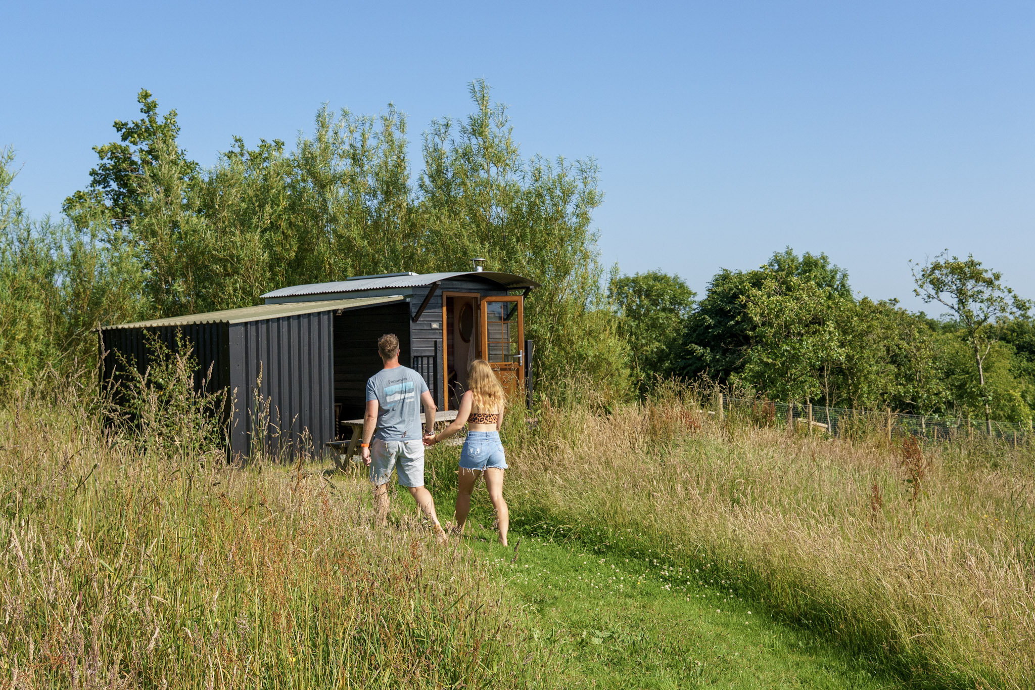 Couple walking towards their off grid shepherds hut