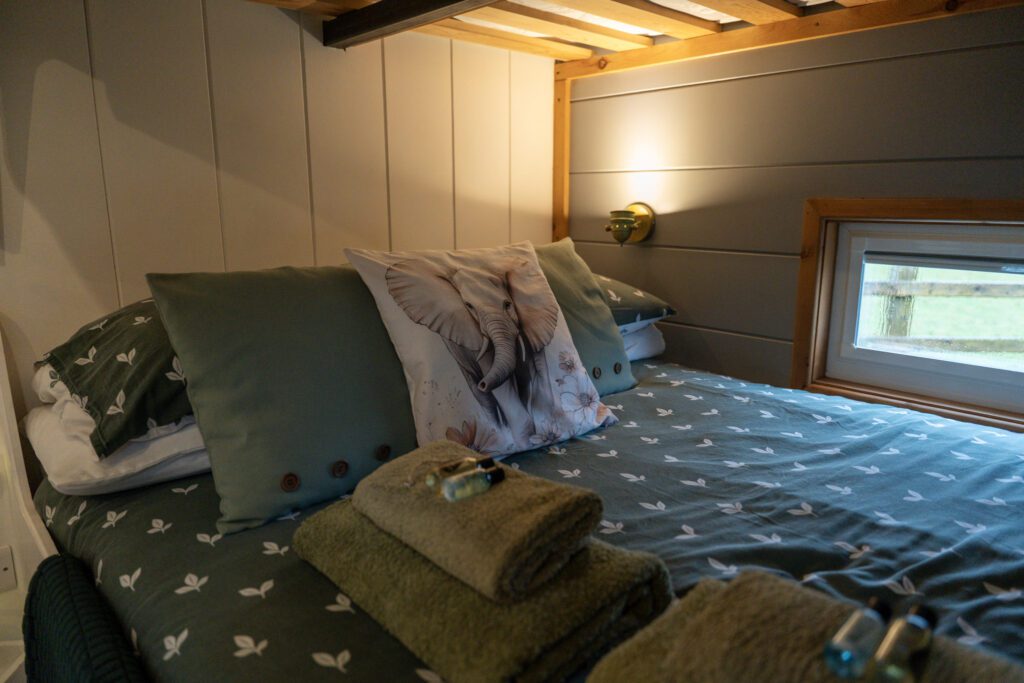 Cosy shepherd hut interior and double bed overlooking welsh farmland