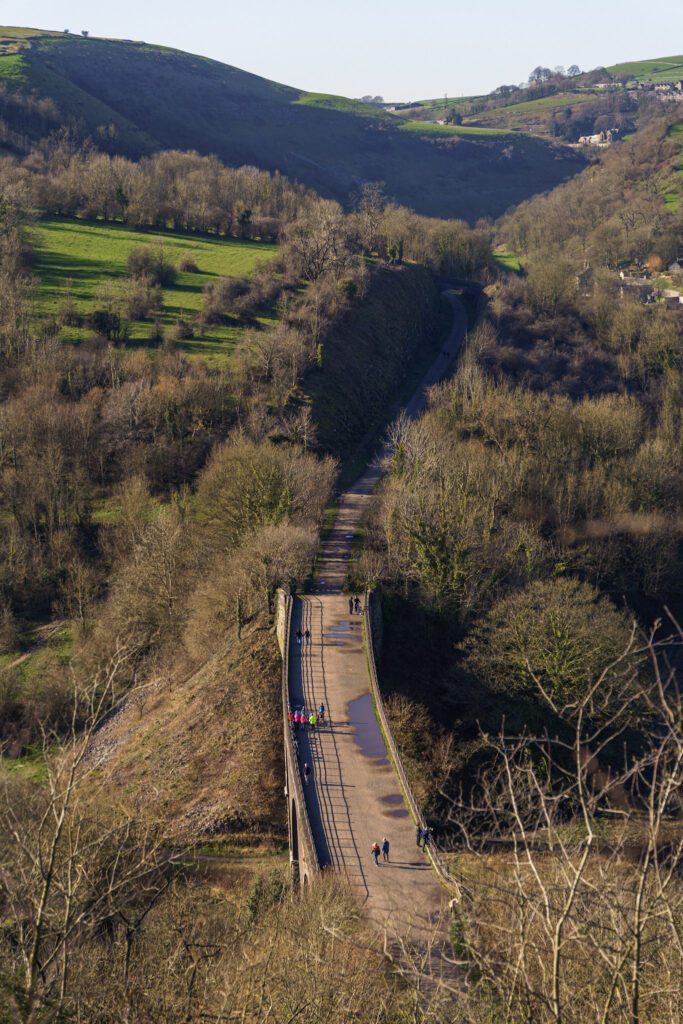 View onto the Monsal viaduct and valley below, people walking across the bridge