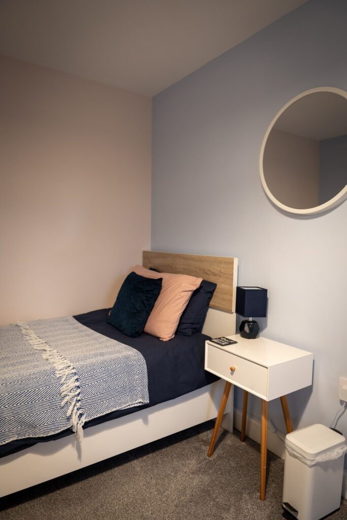 1 of the single beds in the twin bedroom, bedside table, lamp and mirror