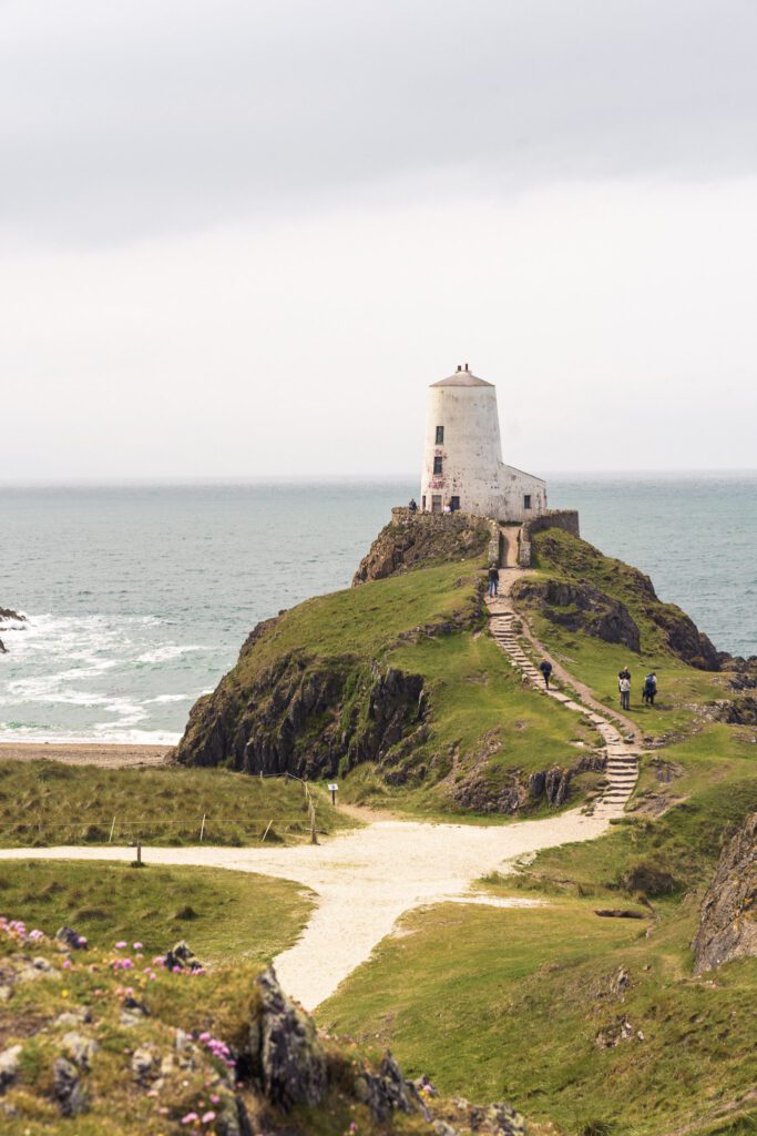 lighthouse on a hill overlooking the sea, steps leading uptight it and a beach cove to the left