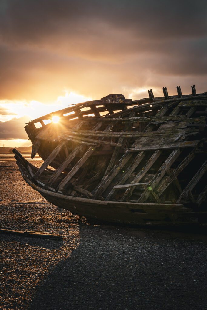 Shipwreck partially blocking the sunset on Dulas Bay