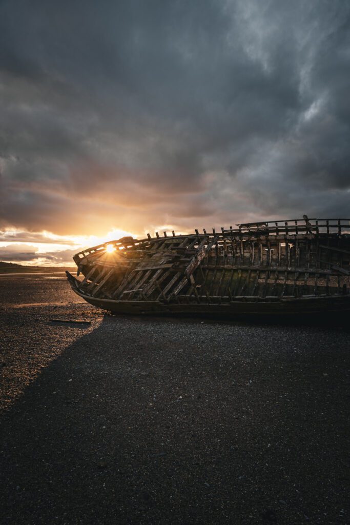 Moody skies, golden sunset rays on a shipwreck on the beach