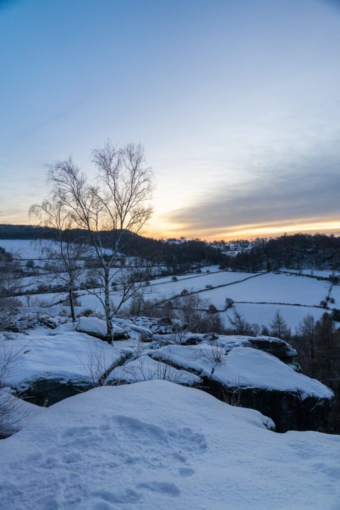 Snowy sunrise at Cratcliffe Tor, with snow covered fields and rocks all around