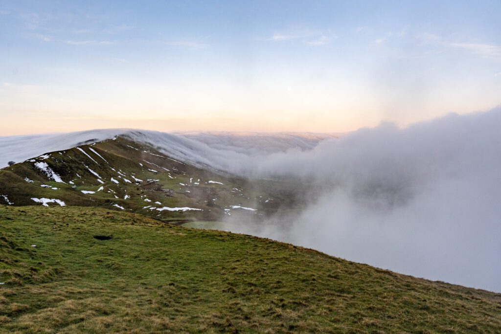 cloud rolling over a snowy mam tor and the great ridge early on a winters morning
