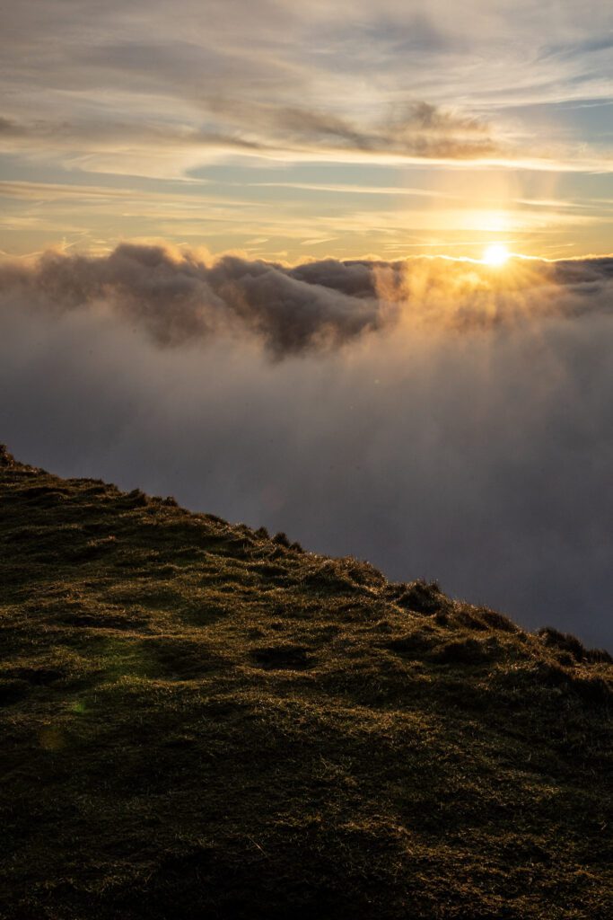 Rolling cloud in the Mam Tor valley with a golden sunrise glow peaking above the clouds
