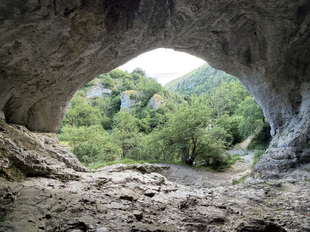 Large cave on the Dovedale valley framing the landscape towards the river and beyond