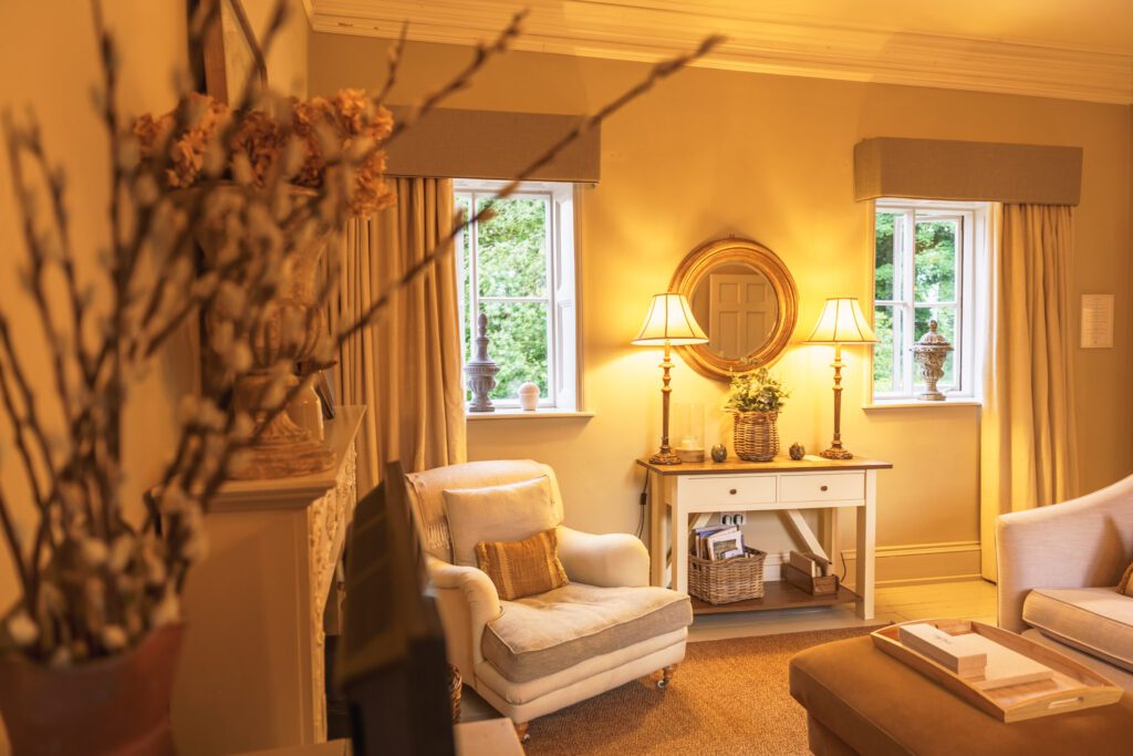 A warm and inviting cottage living room, with cream seating, a basket of books and dominos