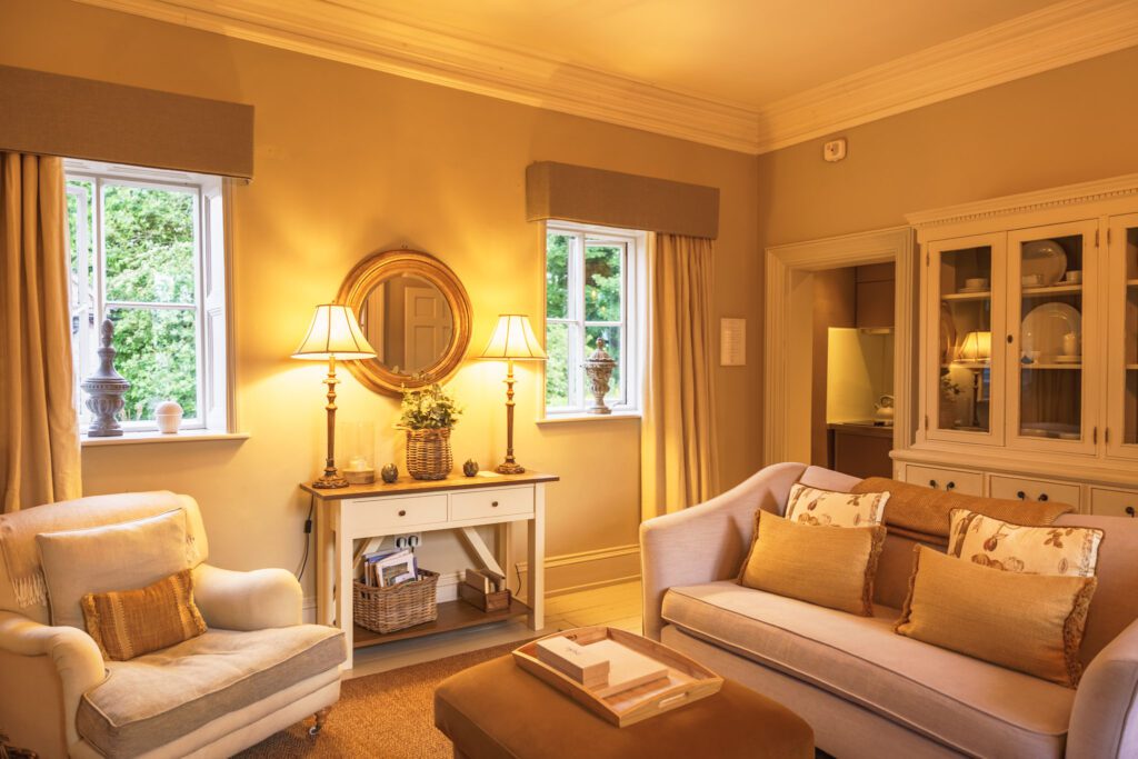 A warm and inviting cottage living room, with cream seating, a basket of books and dominos