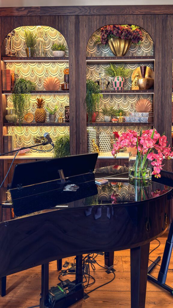 Beautiful piano with fresh flowers sitting on the top and behind in the cabinets
