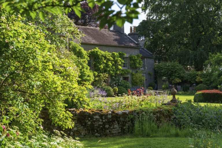Alstonefield manor, in beautiful lush gardens with flowers and stone statues
