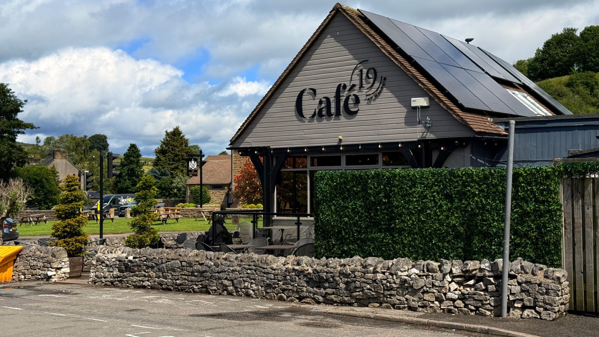 Exterior of Cafe 19 at Calver crossroads, Peak District, with outdoor seating and dry stone wall