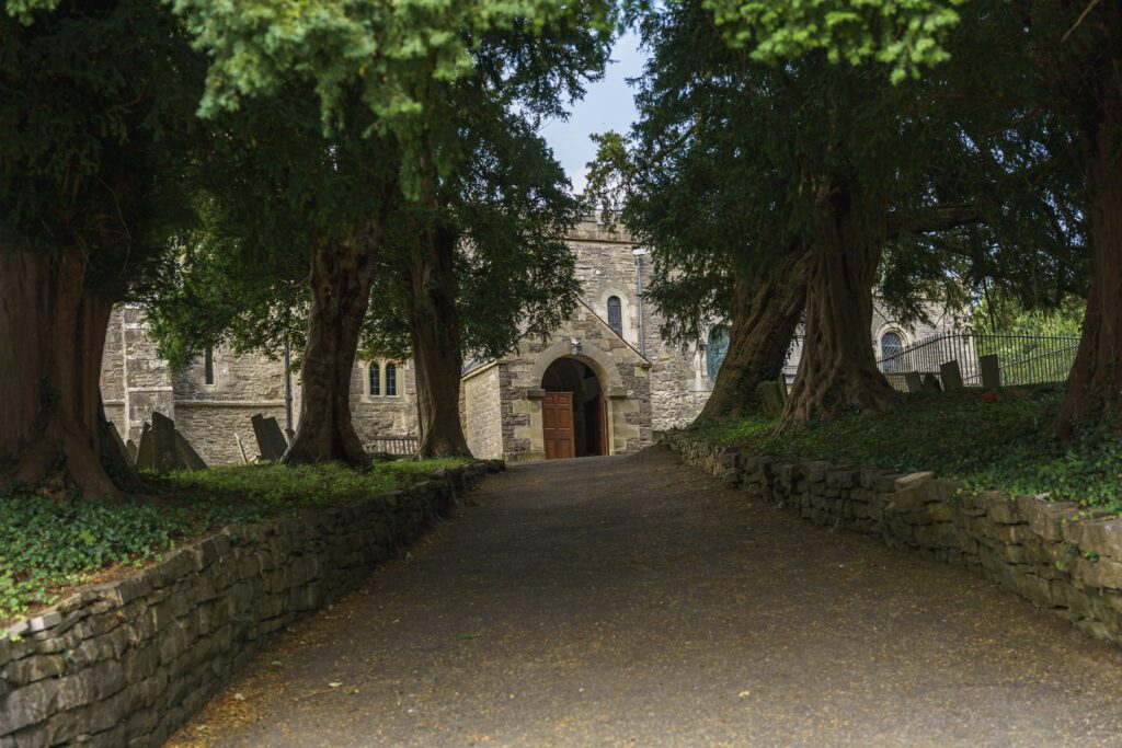 Shot from tree lined path up towards Tissington Church