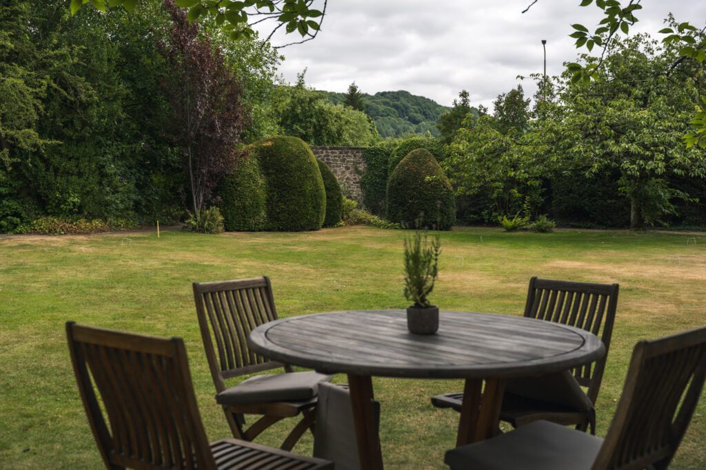 Short croquet lawned area behind the Peacock at Rowsley, with dining tables and well kept garden borders
