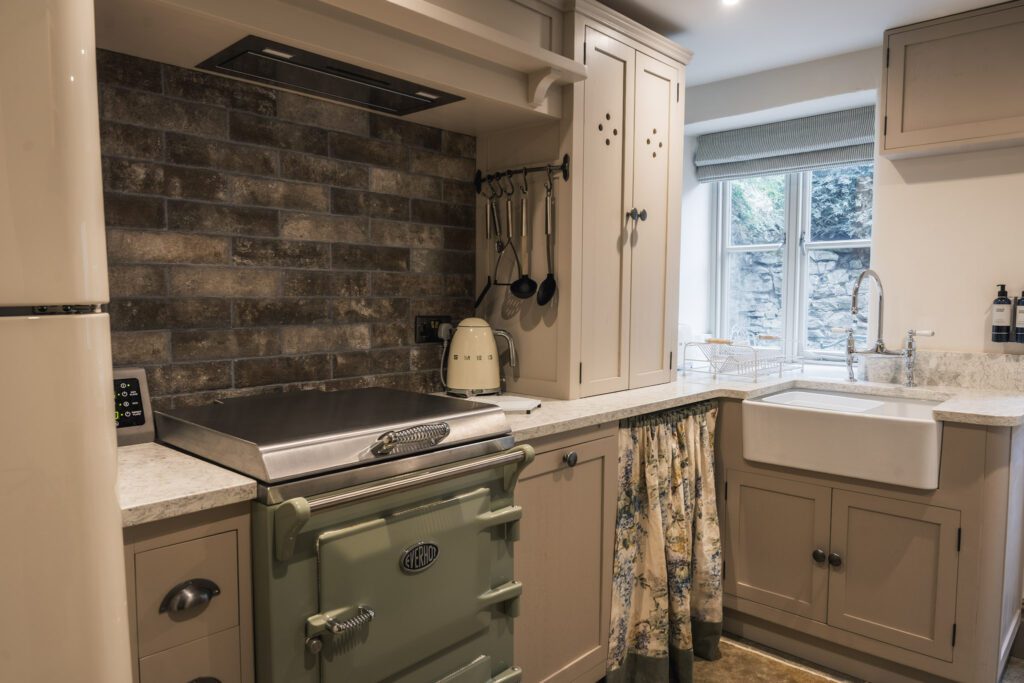 Country kitchen with cream units and a sage green Everhot oven