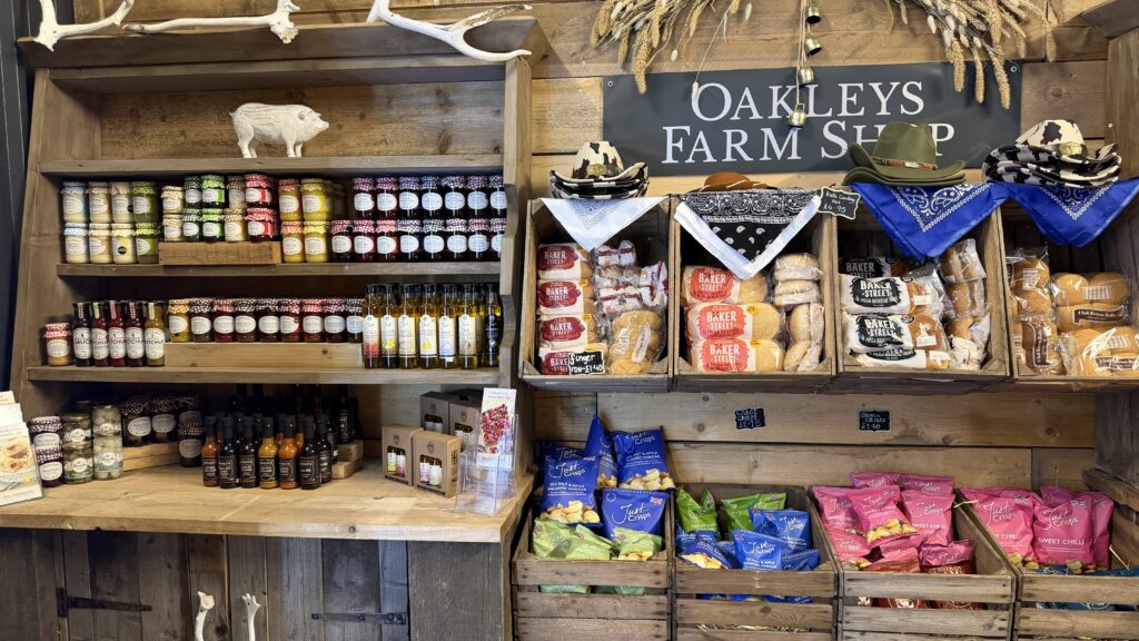 Shelves of local produce and gifts inside Oakleys Farm Shop, with the shop's sign above the counter.