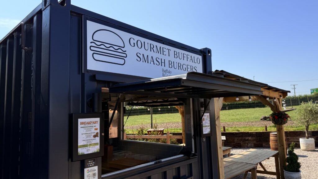 A sign reading Gourmet Buffalo Smash Burgers by Buffalo and Co, mounted on the food stand at Oakleys Farm.