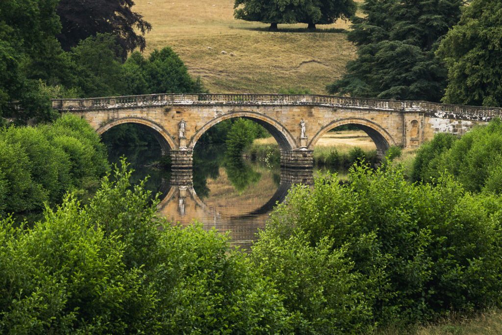 Stone bridge over The River Derwent on the Chatsworth estate with a perfect reflection