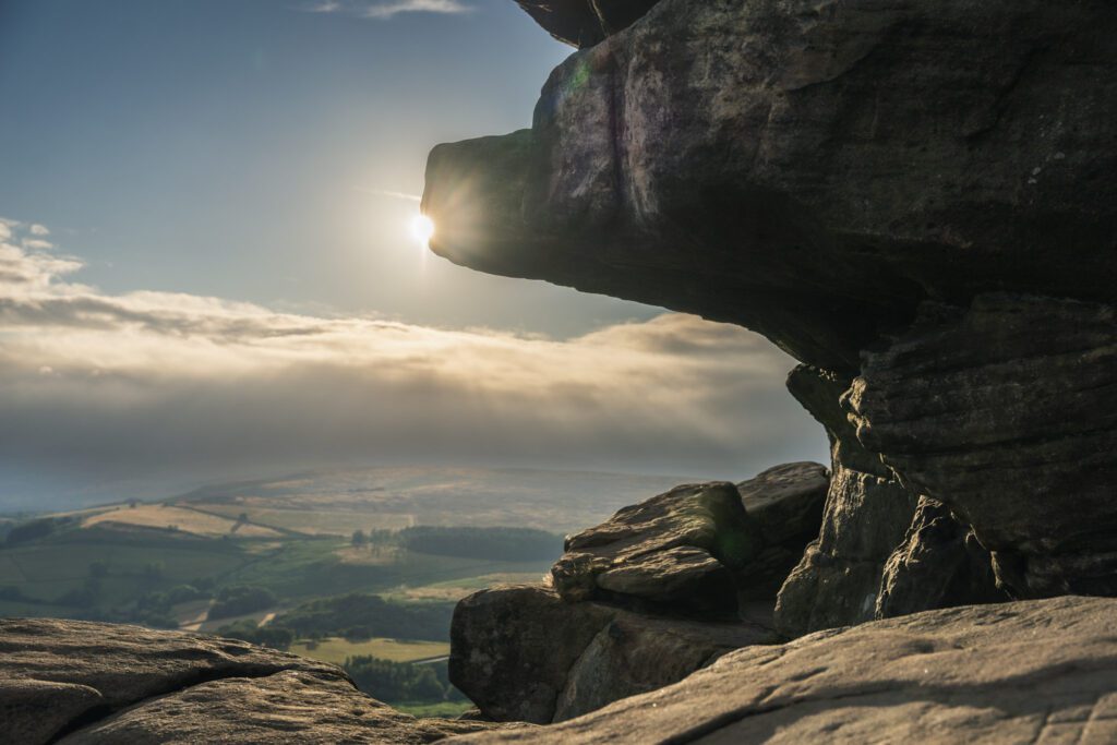 Balcony Cave on Stanage Edge and the sun shining through moody skies
